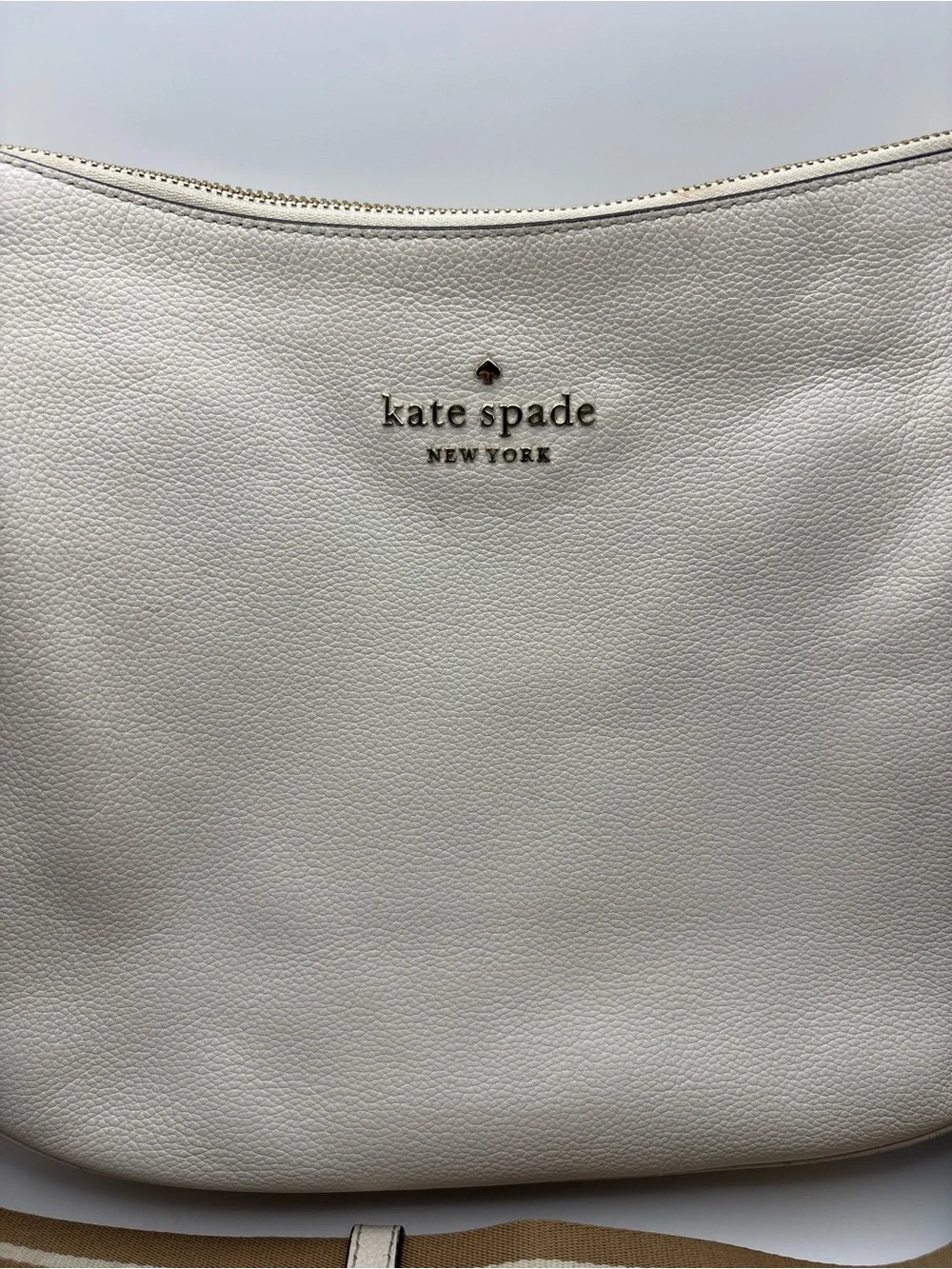 Kate Spade New York cream leather crossbody bag featuring a striped webbing Stra